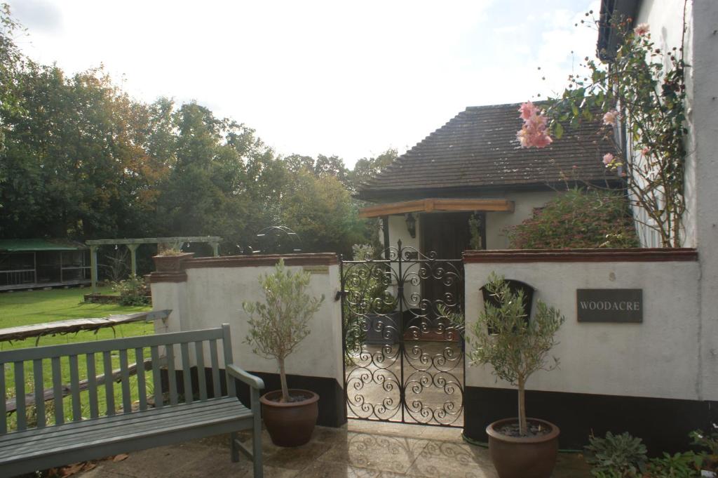 un jardín con un banco y una puerta con árboles en Woodacre B & B, en Arundel