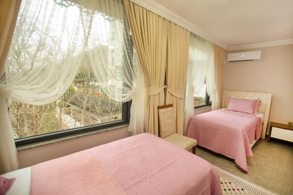 um quarto com 2 camas cor-de-rosa e uma janela em Jolnar garden hotel em Macka