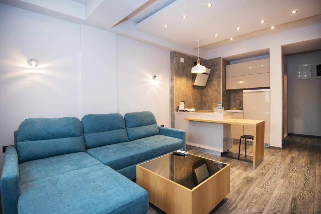 Il comprend un salon avec un canapé bleu et une cuisine. dans l'établissement Hotel Vlaho, à Skopje