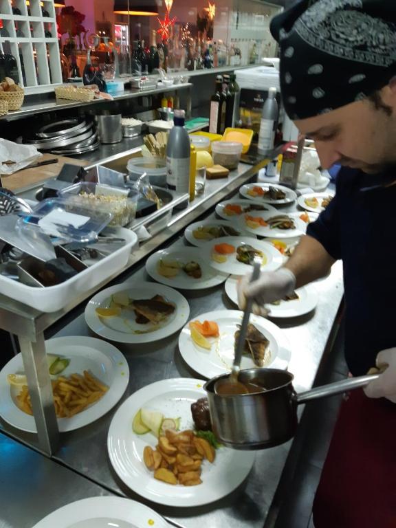 a person preparing food in a kitchen with plates of food at Boutique Villa Revelin in Pag