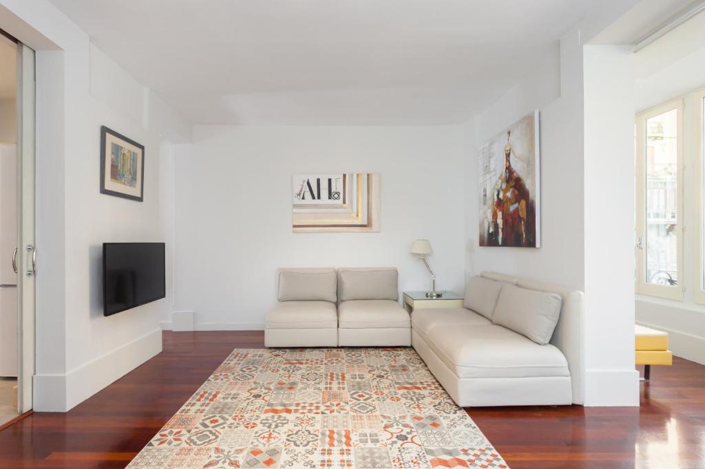 a white living room with a couch and a tv at Art House Granvia in Barcelona
