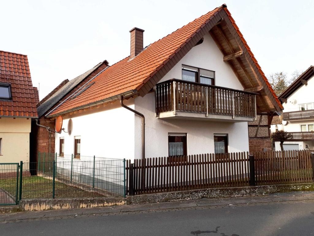 Biały dom z balkonem i ogrodzeniem w obiekcie Ferienhaus Waldschmidt w mieście Momlingen