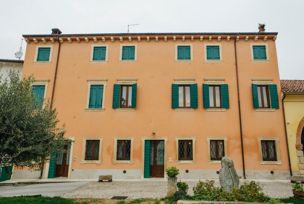 un grande edificio arancione con persiane verdi di B&B Corte Dal Colle a Caldiero