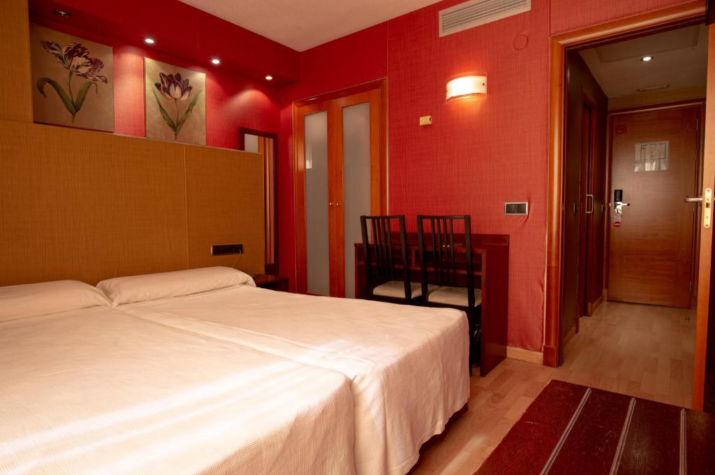 a bedroom with a white bed and red walls at Hotel Villa de Barajas in Madrid