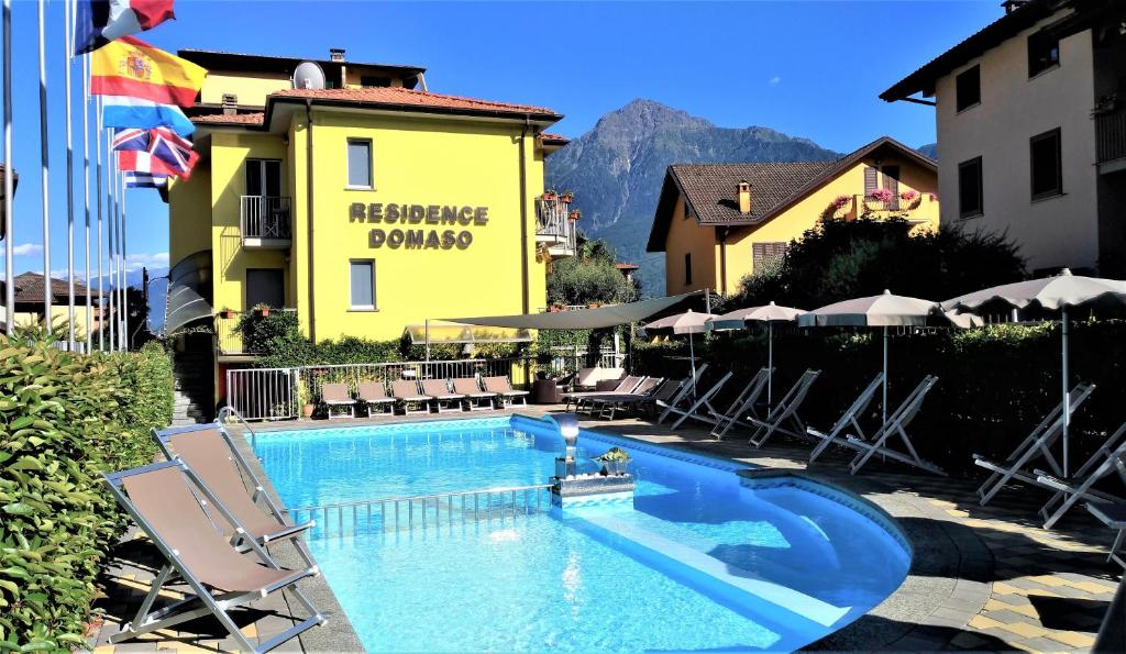 a swimming pool with chairs and a yellow building at Residence Domaso in Domaso