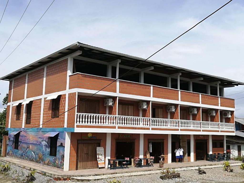 Hotel Acuali Nuqui في نوكوي: مبنى من الطوب كبير مع شرفة على الجانب