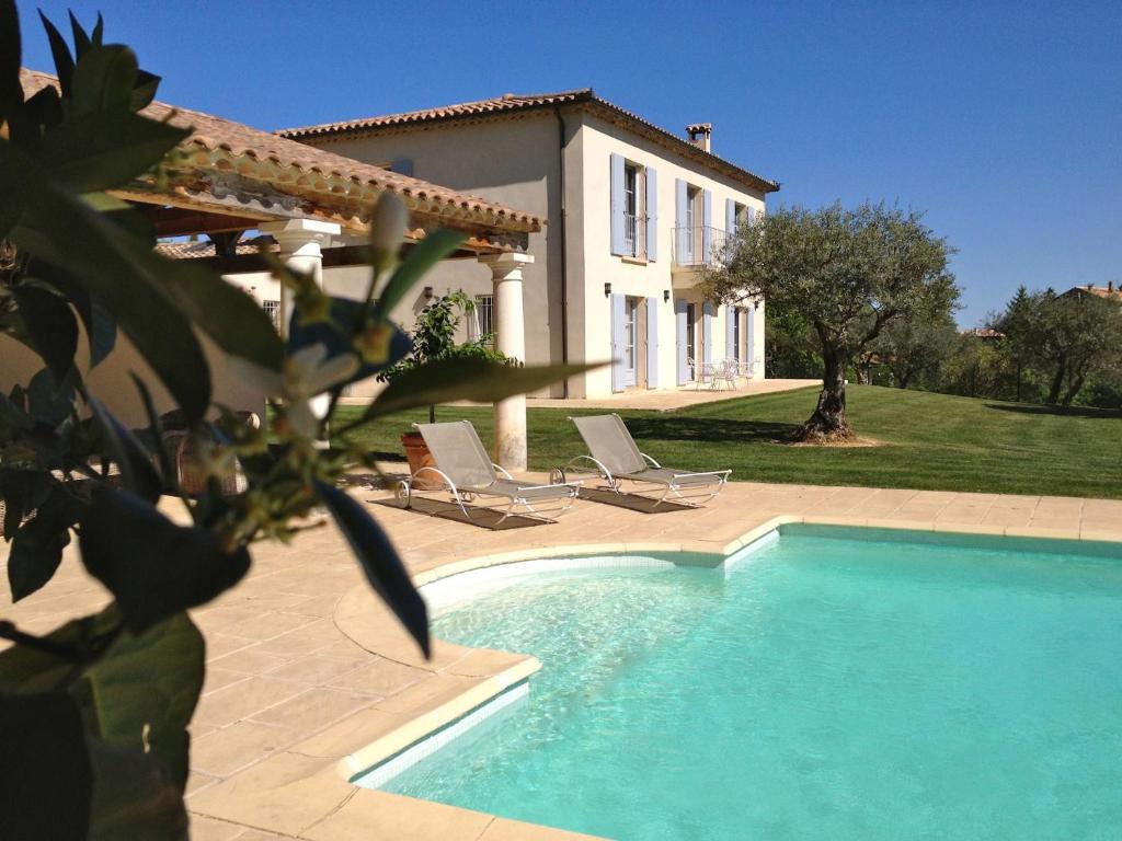a house with a swimming pool and two lounge chairs at La Bastide d'Andrea in Martignargues