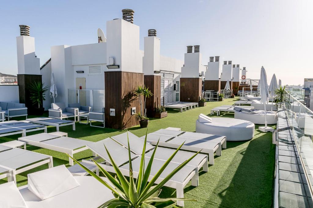 a rooftop patio with white chairs and tables on a roof at Exe Las Palmas in Las Palmas de Gran Canaria