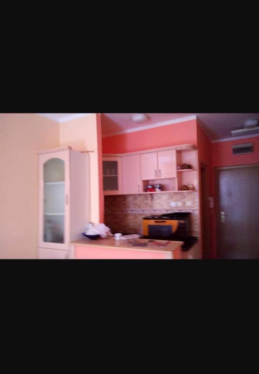 a kitchen with red walls and white cabinets at Apartman S in Palisat