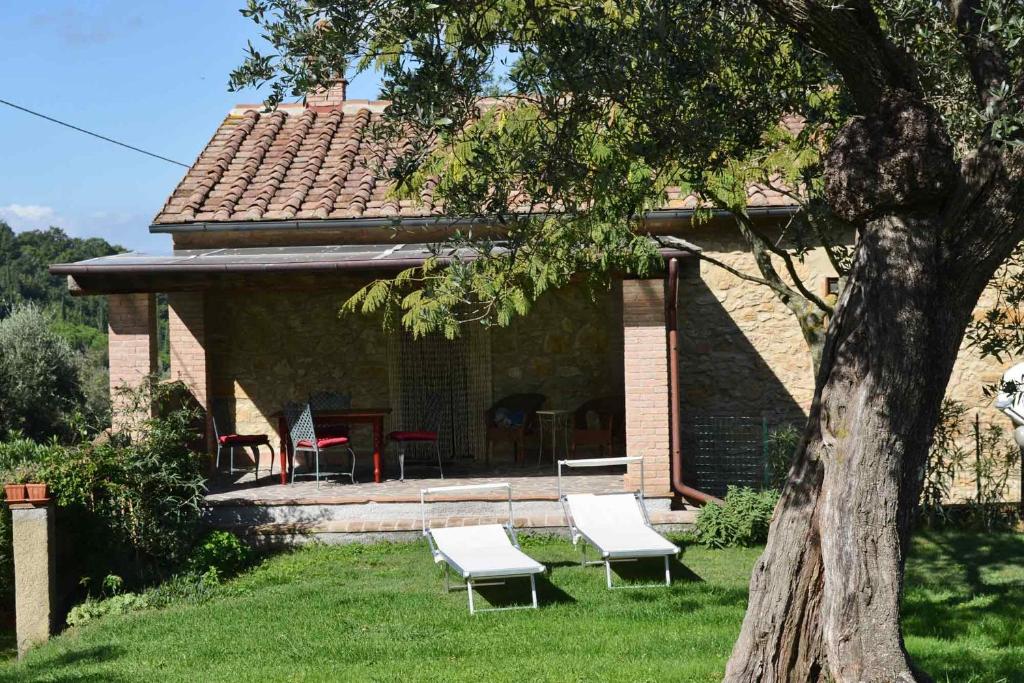 ein Haus mit zwei weißen Stühlen und einem Tisch in der Unterkunft CASE&COLLINE Chiusaperi-Girasole in Montescudaio