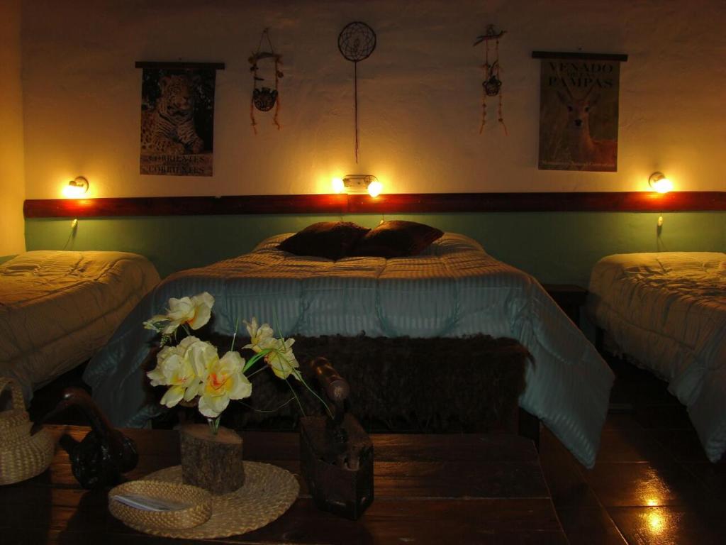 sypialnia z 2 łóżkami i łóżkiem z kwiatami w obiekcie Hospedaje San Cayetano w mieście Colonia Carlos Pellegrini