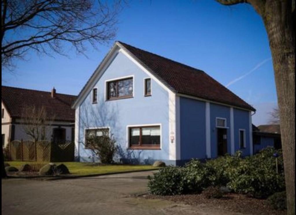 ein weißes und blaues Haus mit einem Baum in der Unterkunft Ferienwohnung Esenshamm in Nordenham