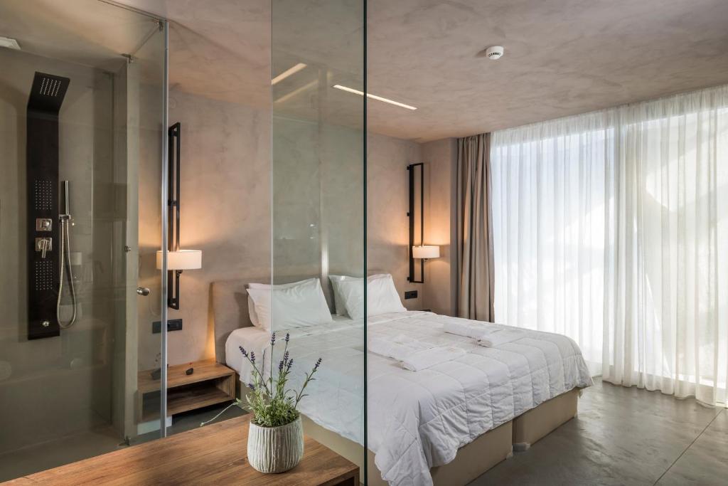 - une chambre avec un lit et une douche en verre dans l'établissement Icarus Hotel, à Kalamaki