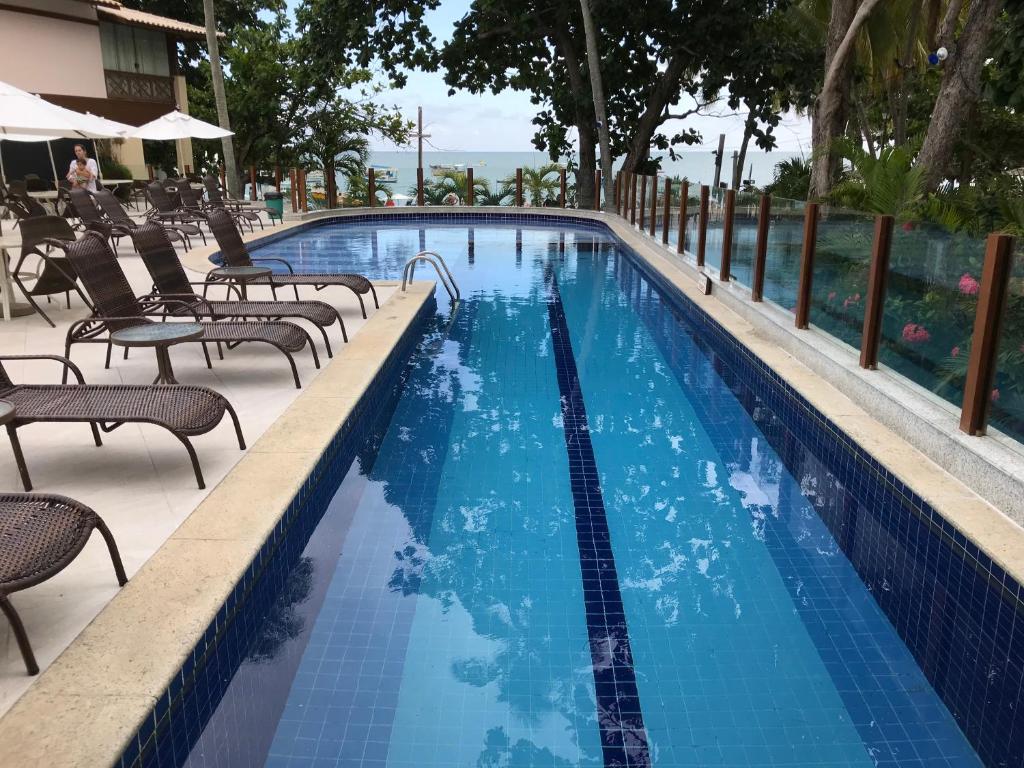 a large swimming pool with chairs at Porto Praia do Forte in Praia do Forte