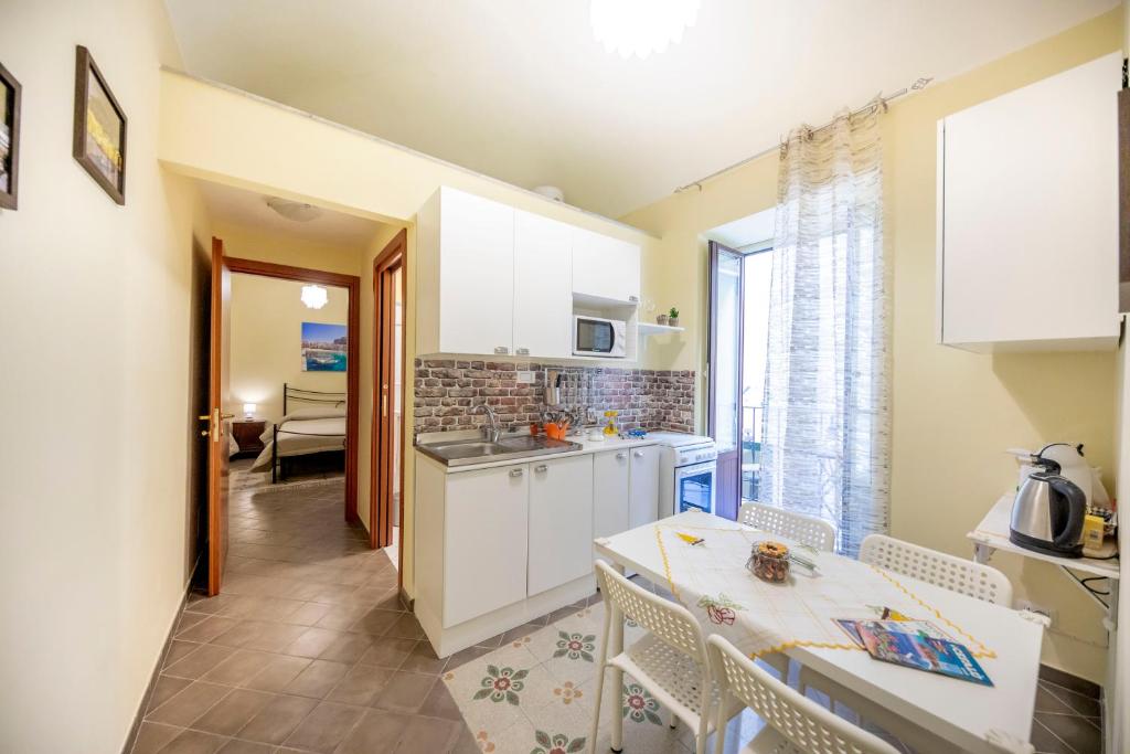 una cucina con armadi bianchi, tavolo e sedie di Sicilian Dream Apartments a Cefalù