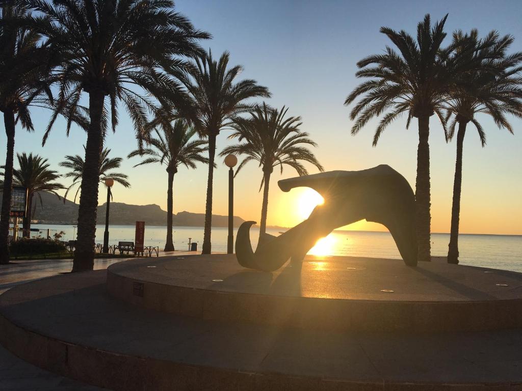 a dolphin statue in front of the ocean with palm trees at Albir Vacation in Albir