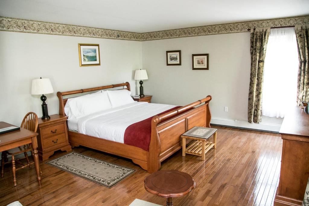 a bedroom with a bed and a desk and a window at The Harbour House in Charlottetown