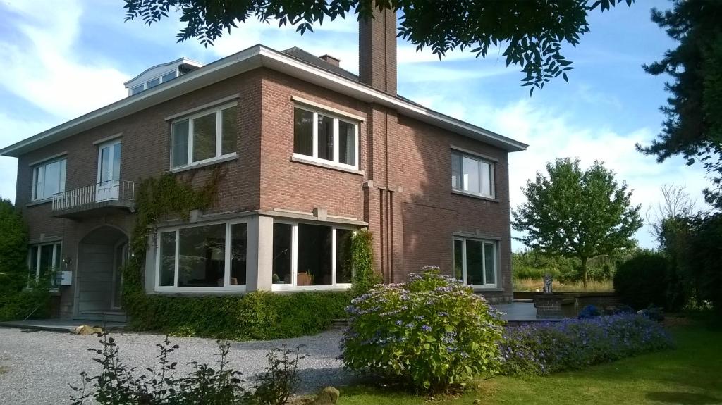 a red brick house with a chimney at De tuin van Agatha in Kortessem