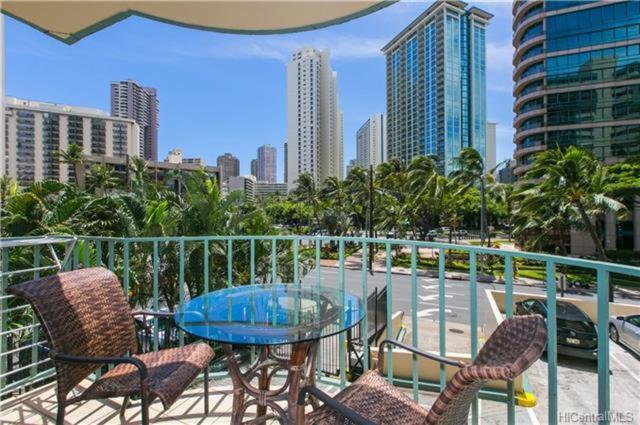 patio con mesa de cristal y sillas en el balcón en Waikiki 2BR King Beds Short Walk to Convention and Beaches, en Honolulu