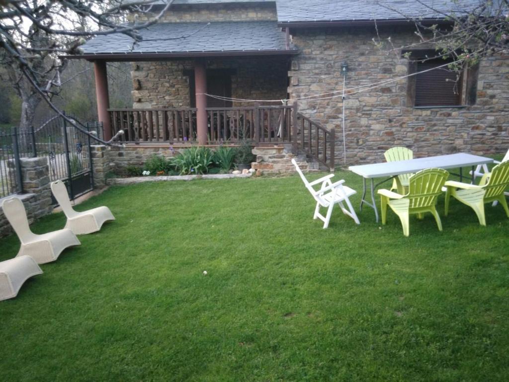 un patio con una mesa y sillas en el césped en Casa rural el Molino del Botero en Coso