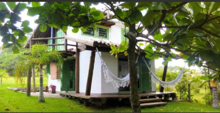a green and white house with a net at Casa do Eduardo in Praia do Rosa