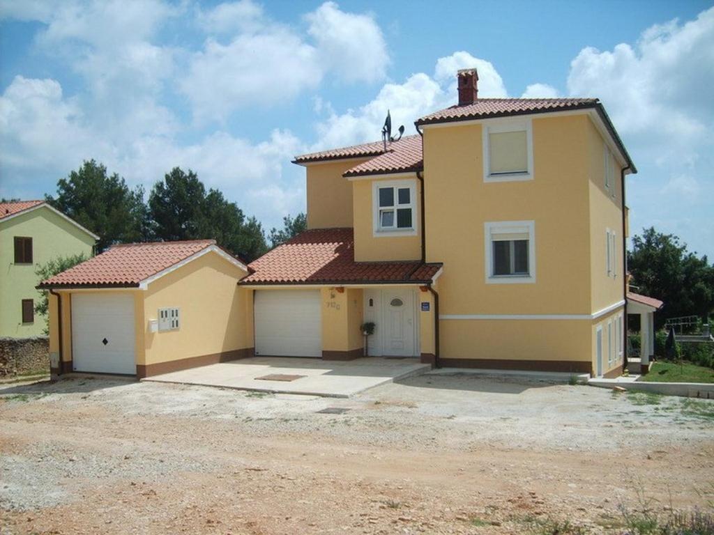 a large yellow house with two garage at Apartment Liznjan 4 in Ližnjan