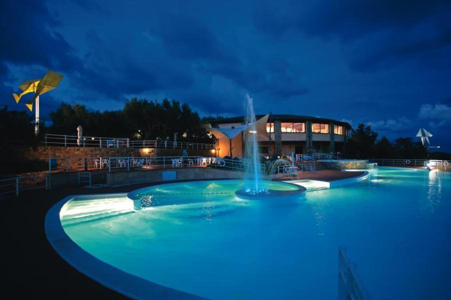 a swimming pool with a fountain in front of a building at Happy Village in Marina di Camerota