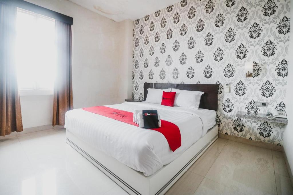 1 dormitorio con 1 cama blanca grande con almohadas rojas en RedDoorz Plus near Universitas Negeri Makassar, en Makassar