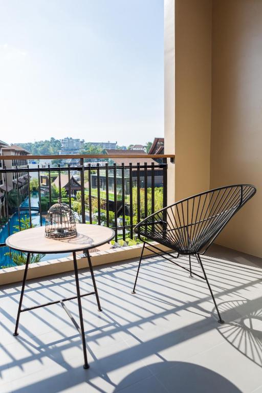 a chair and a table on a balcony with a view at Aurico Kata Resort & Spa - SHA Extra Plus in Kata Beach