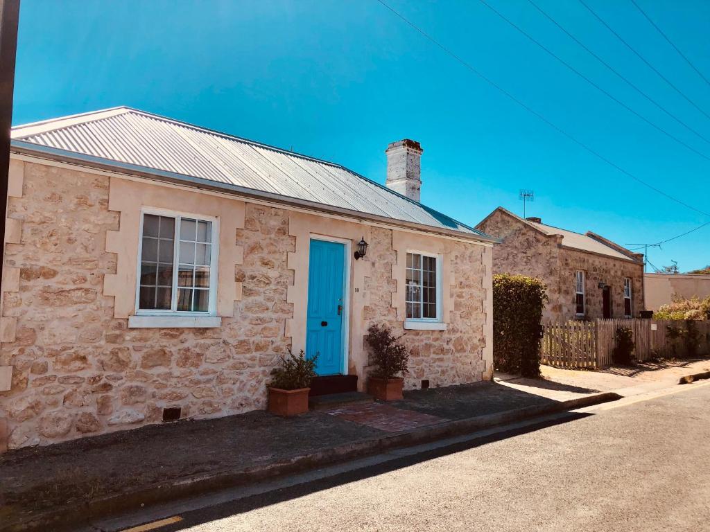 une maison en pierre avec une porte bleue dans une rue dans l'établissement Goolwa Mariner’s Cottage - Free Wifi and Pet Friendly - Centrally located in Historic Region, à Goolwa