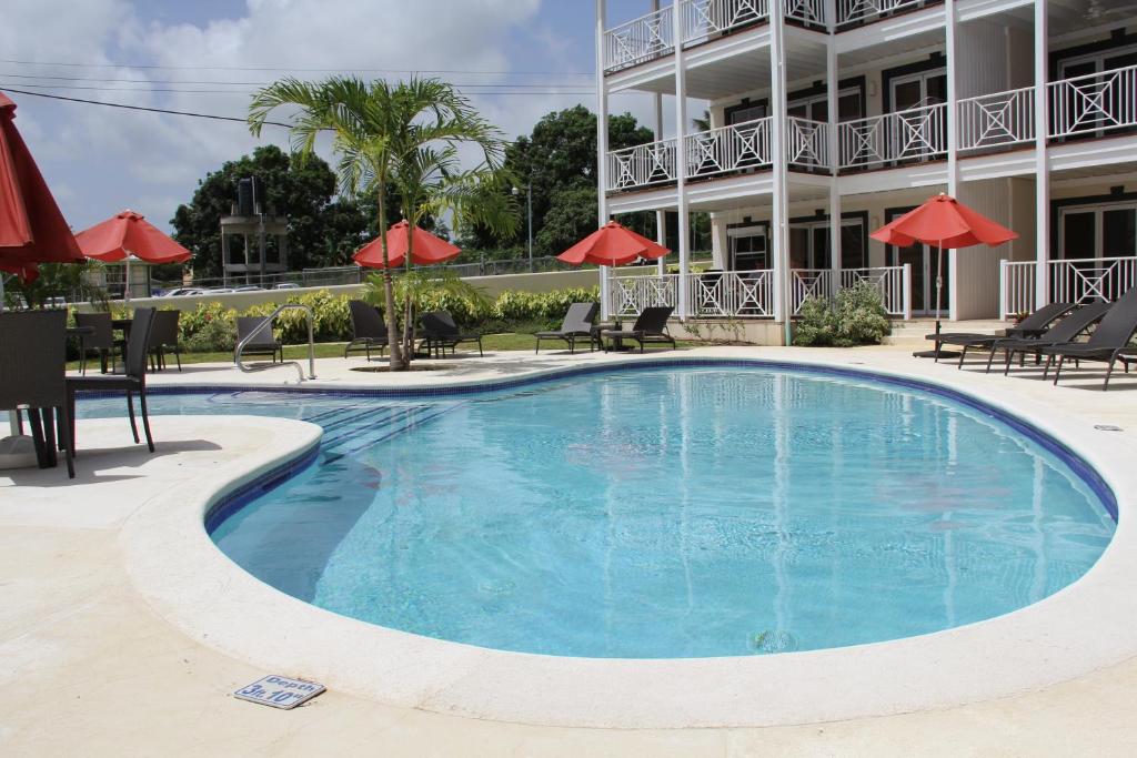 a swimming pool in front of a hotel with red umbrellas at Lantana Resort Barbados by Island Villas in Saint James