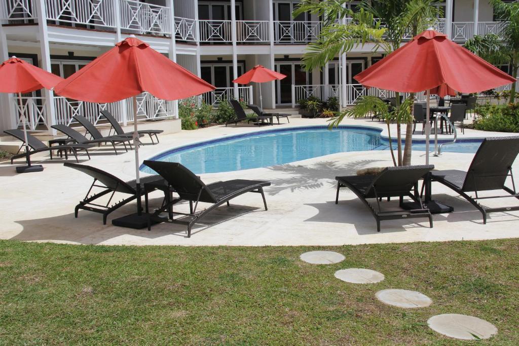 a group of chairs and umbrellas next to a pool at Lantana Resort Barbados by Island Villas in Saint James