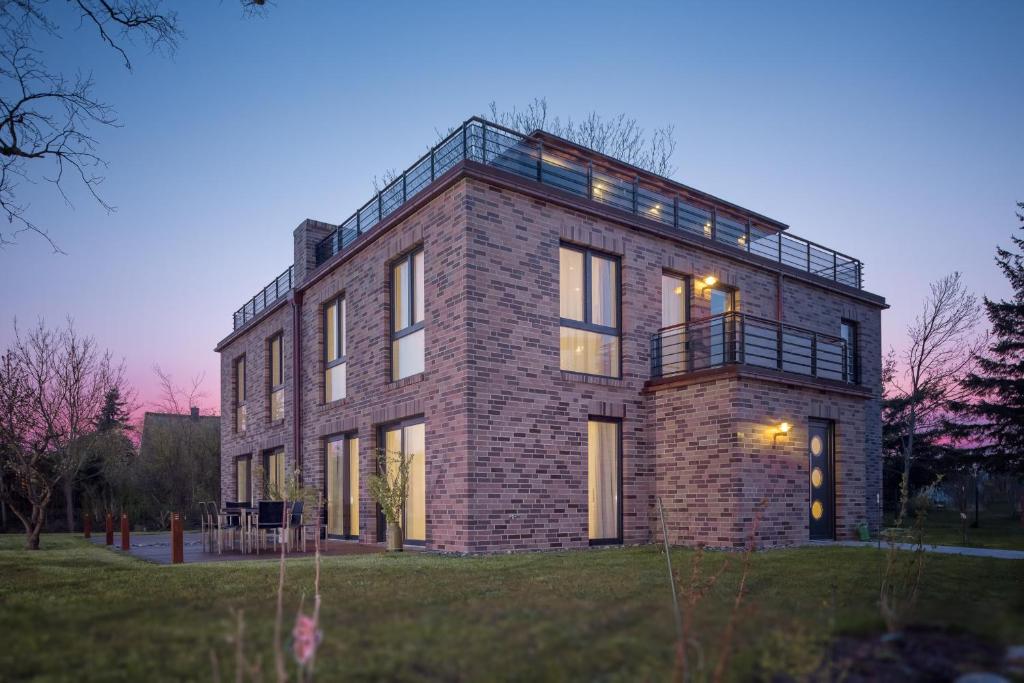 a brick building with a balcony on top of it at Villa Lotsenhäuser Rügen - Luxus Ferienhaus - 3 Schlafzimmer - Sauna - Dachterrasse mit Boddenblick in Breege