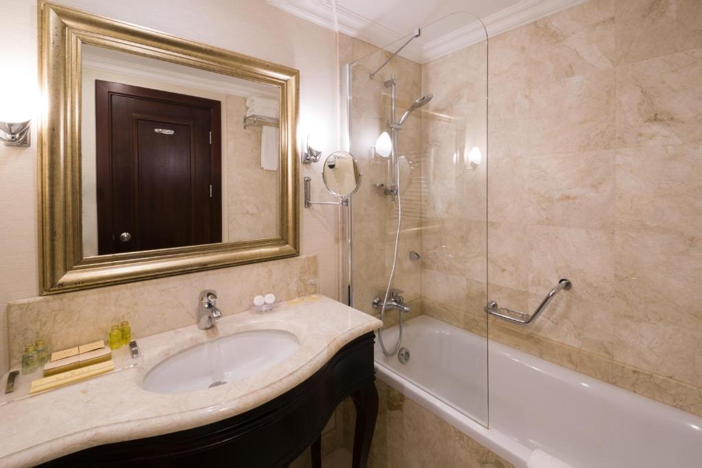 a bathroom with a sink and a shower and a mirror at Rixos-Prykarpattya Resort in Truskavets