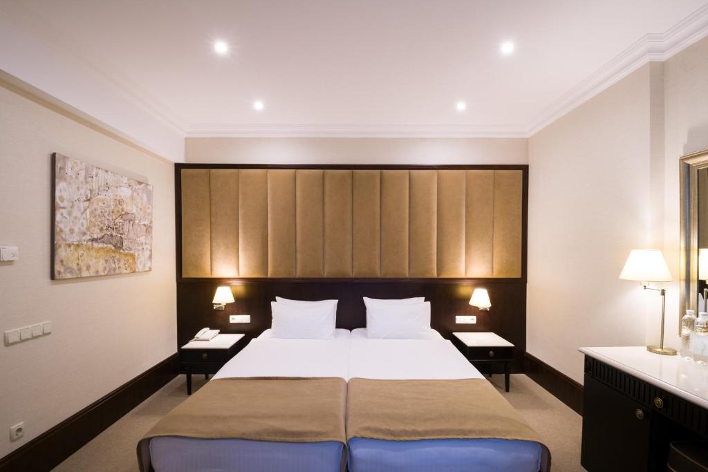 a hotel room with a large bed and two tables at Rixos-Prykarpattya Resort in Truskavets