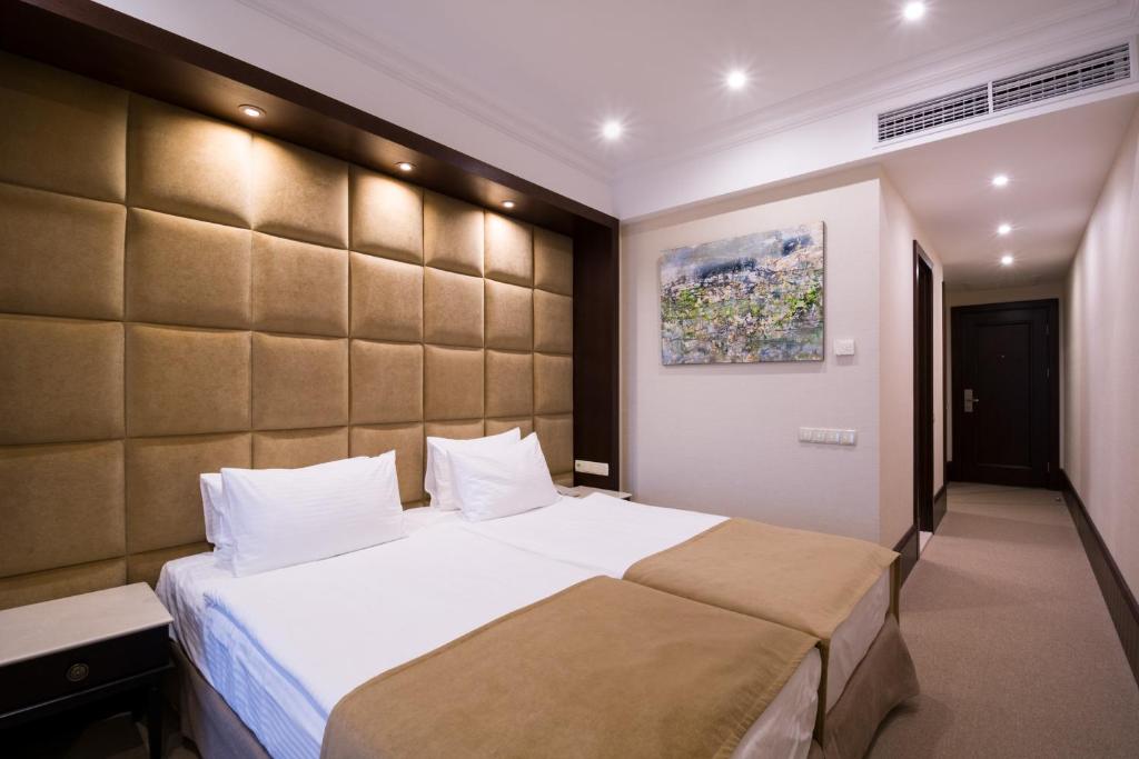 a bedroom with a large bed with a large headboard at Rixos-Prykarpattya Resort in Truskavets