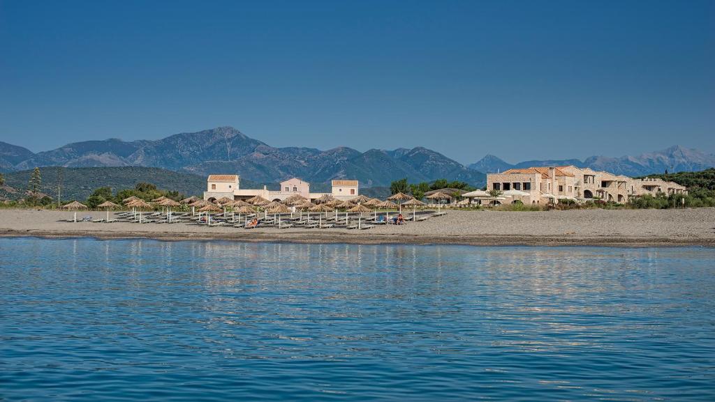 einen Strand mit Stühlen und Sonnenschirmen am Ufer in der Unterkunft Castello Antico Hotel in Gythio