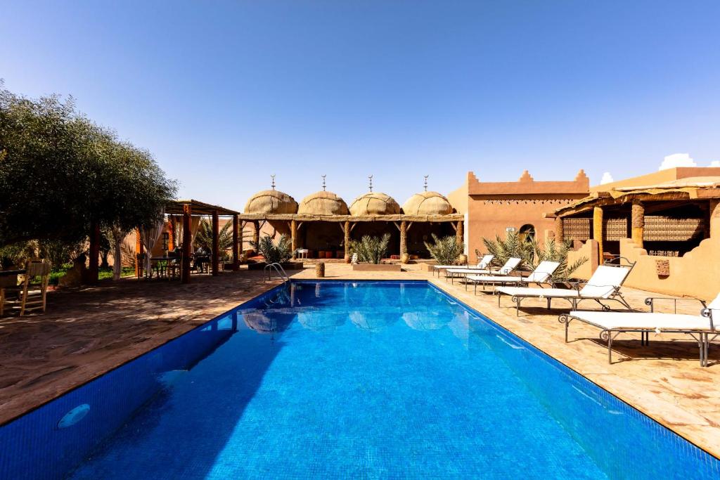 a large swimming pool with chairs and a building at Hotel Kasbah Sahara in Mhamid