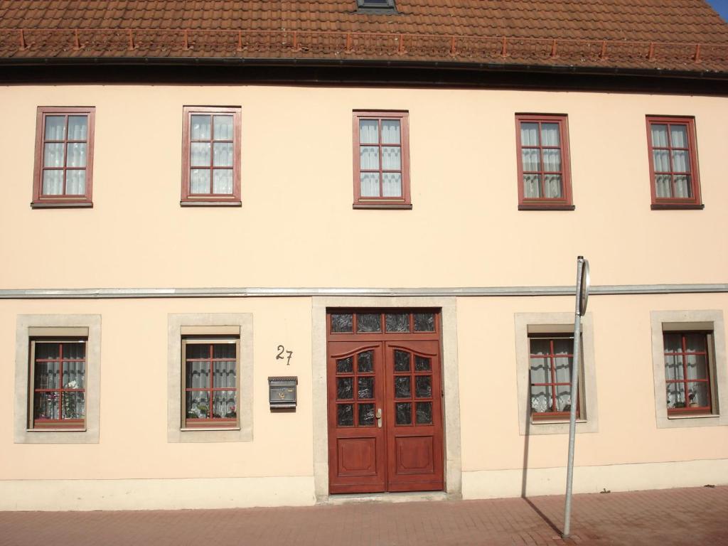 a white building with a red door and windows at Ferienwohnung Eckoldt in Eisenberg