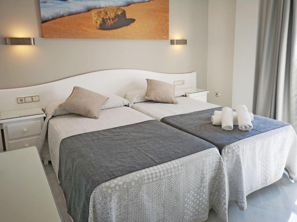 Habitación blanca con 2 camas y toallas. en Hostal Bodega, en Conil de la Frontera