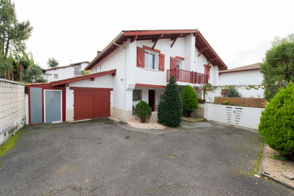 a white house with a red garage at Hermosa casa con terraza y jacuzzi en Hendaya in Hendaye