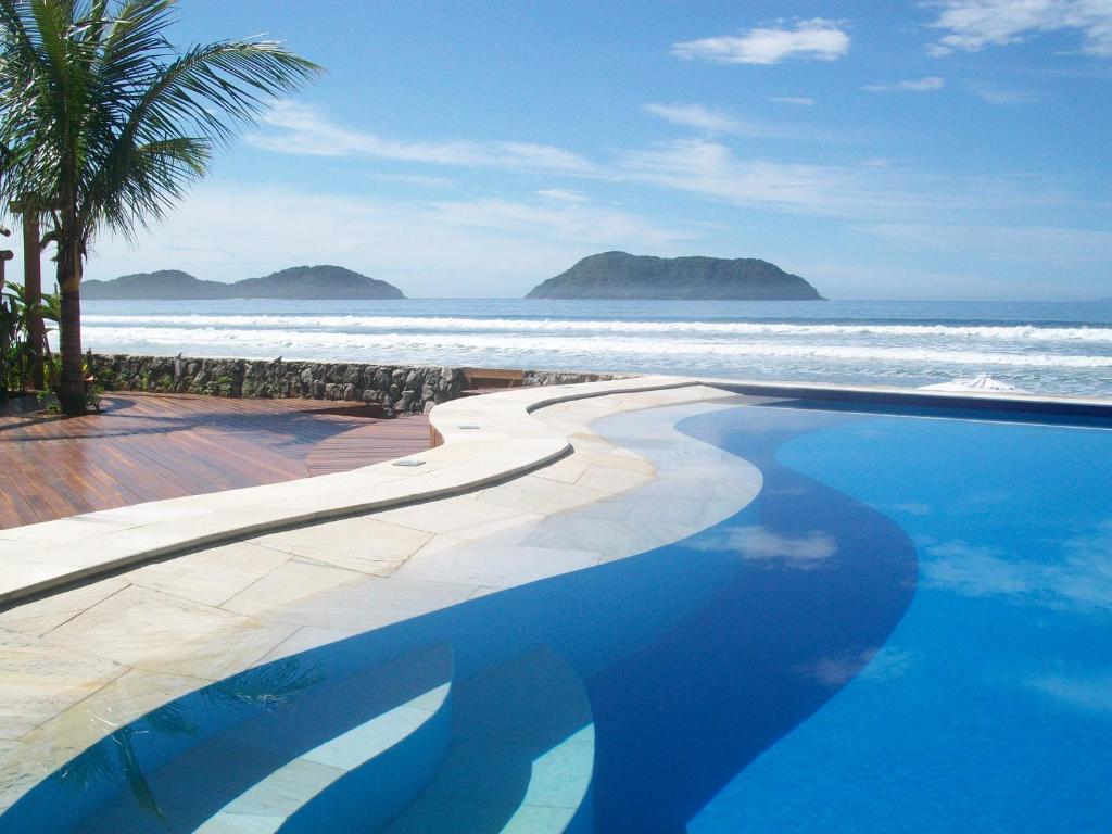 a swimming pool next to a beach with the ocean at Juquehy La Plage Hotel in Juquei