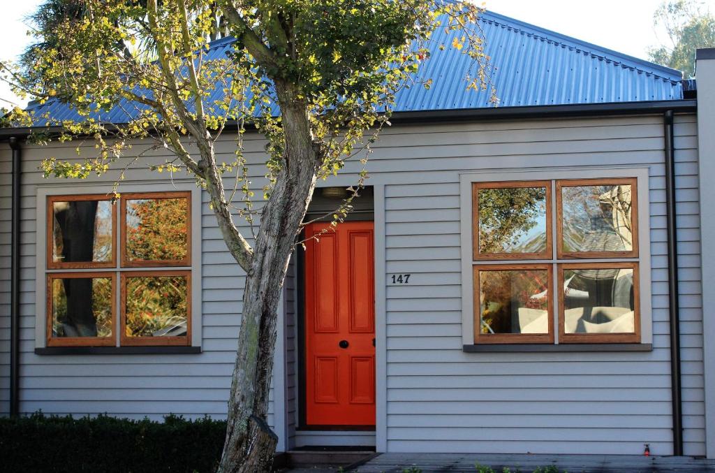 a house with a red door and a tree at Entwhistle Cottage in Christchurch