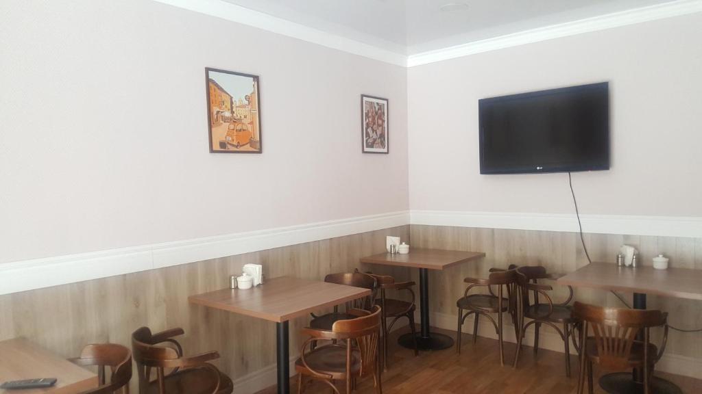 a restaurant with wooden tables and a flat screen tv at Silk Way in Almaty