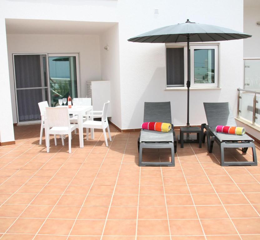 een patio met een tafel en stoelen en een parasol bij Carvoeiro Bay Apartment in Carvoeiro