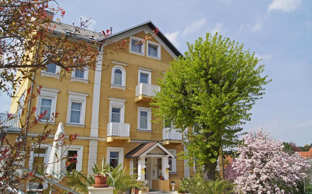 żółty budynek z drzewem przed nim w obiekcie Hotel Hotwagner w mieście Maria Enzersdorf