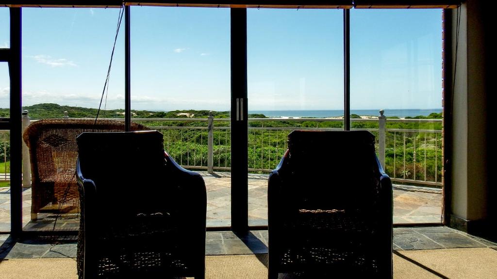 two chairs in front of a window with a view of the ocean at House Haven Guesthouse in Port Elizabeth