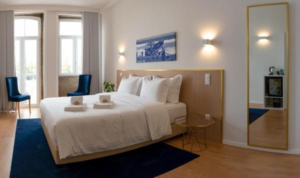 - une chambre avec un grand lit et deux chaises bleues dans l'établissement ó Poboa Guesthouse, à Póvoa de Varzim