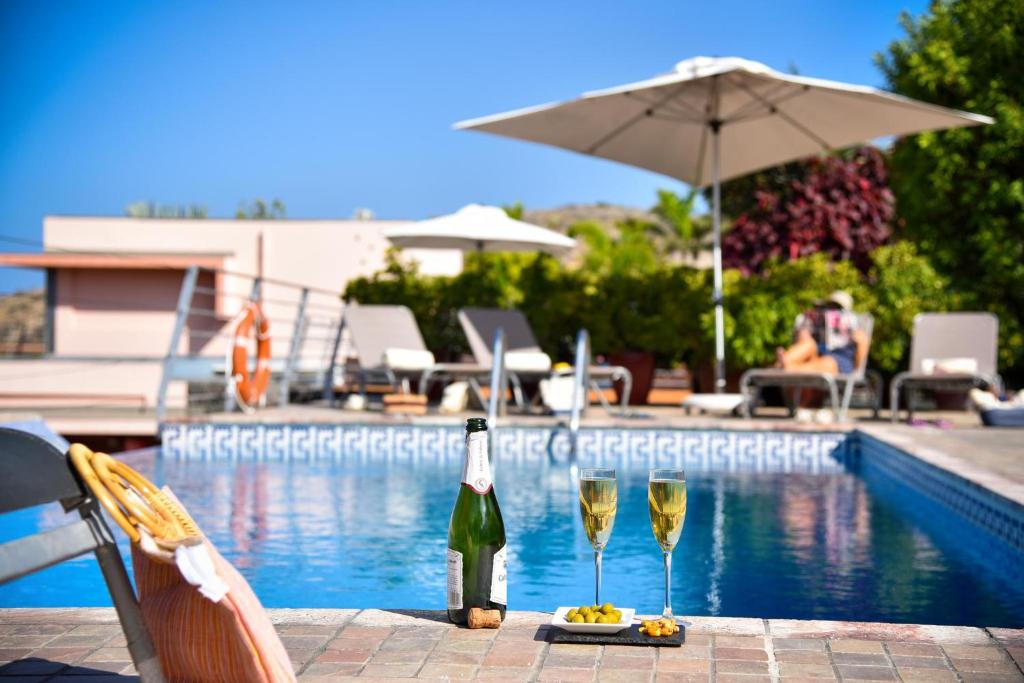 a table with two glasses of wine next to a swimming pool at Villa Gran Canaria Specialodges in Salobre