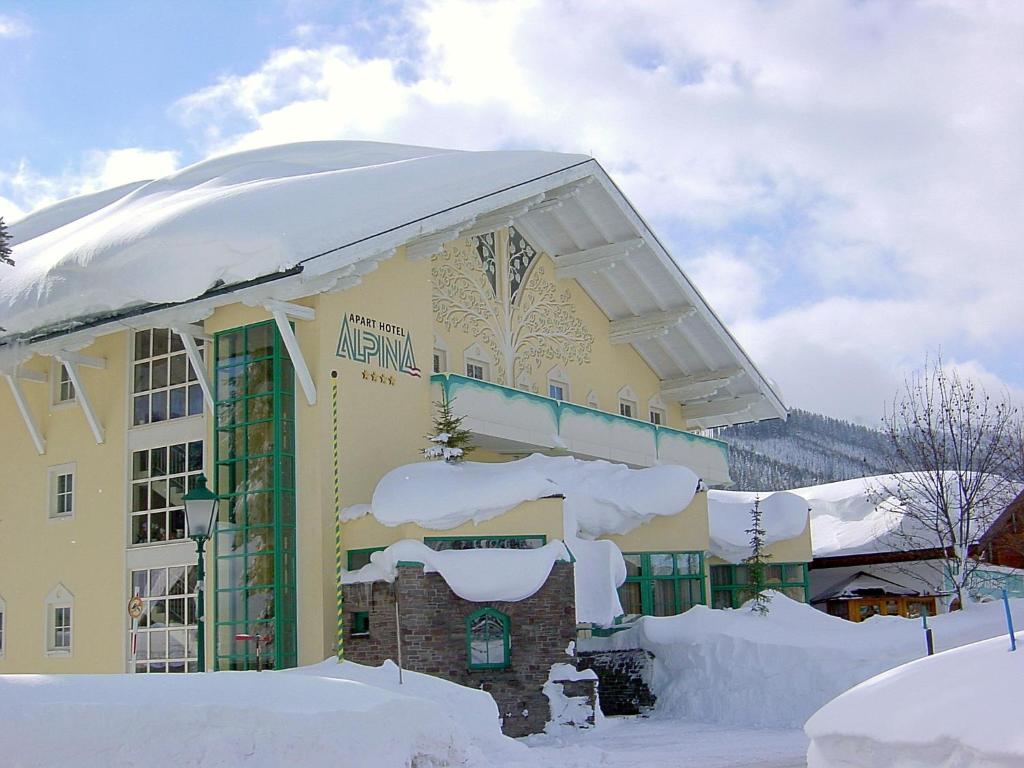 un edificio cubierto de nieve con nieve. en Aparthotel Alpina en Filzmoos